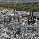 Trabajadores de defensa civil y residentes buscan entre los escombros de edificios derrumbados en la ciudad de Harem, cerca de la frontera turca, provincia de Idlib