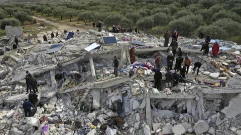 Trabajadores de defensa civil y residentes buscan entre los escombros de edificios derrumbados en la ciudad de Harem, cerca de la frontera turca, provincia de Idlib