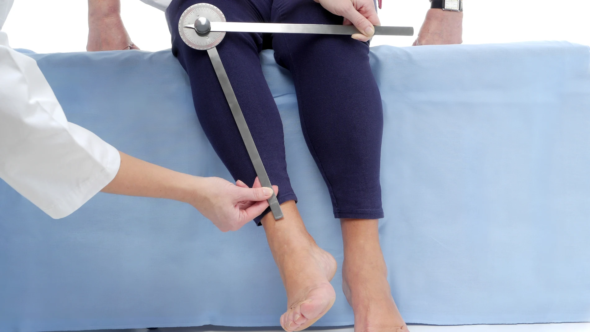Fisioterapeuta midiendo el rango de movimiento activo de la extremidad inferior de una paciente mayor usando un goniómetro manual