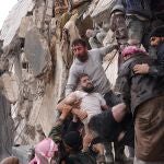 Vecinos rescatan a un superviviente entre los escombros de un edificio derrumbado en la ciudad de Jandaris, en Siria