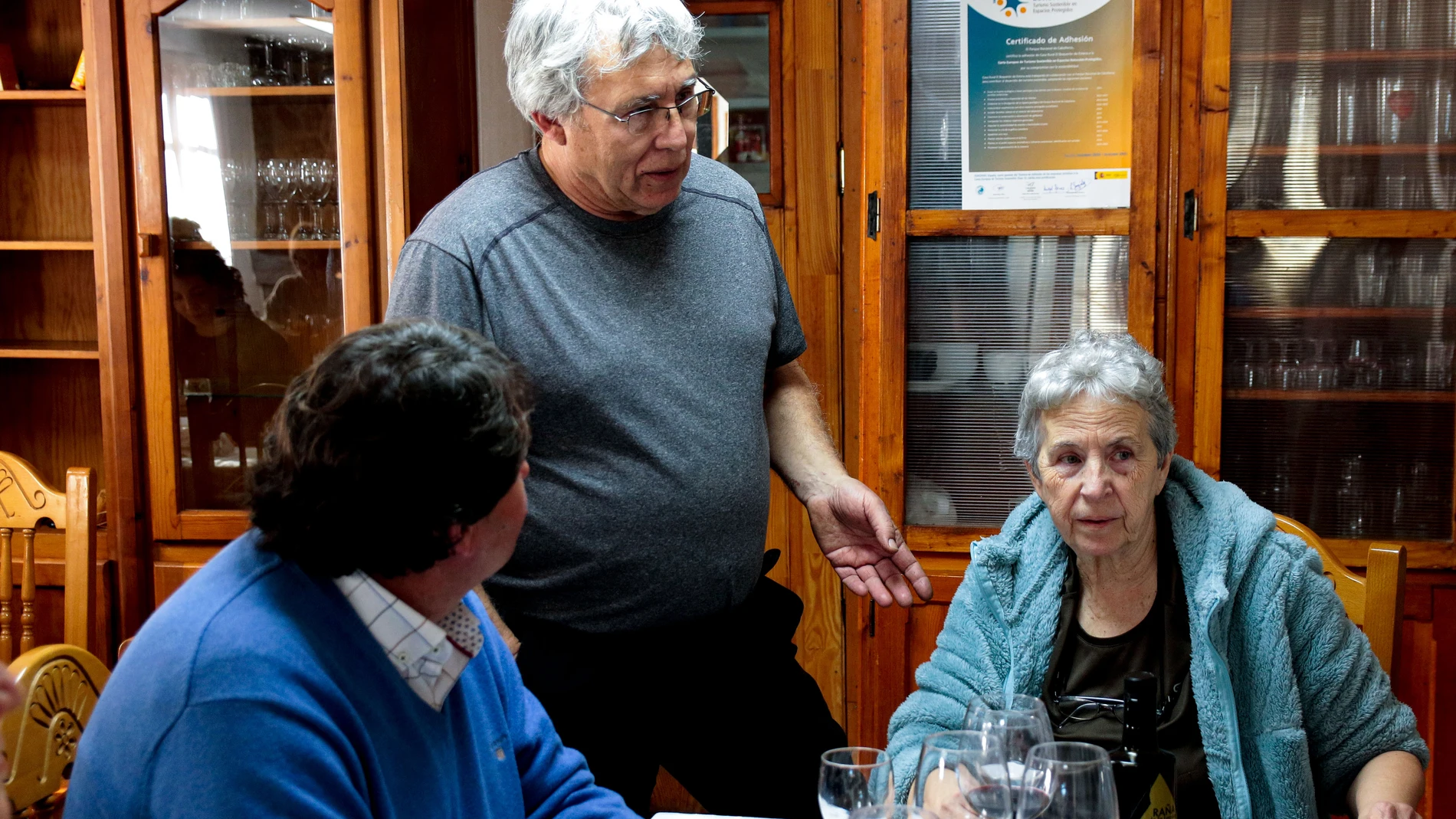 NAVAS DE ESTENA (CIUDAD REAL), 08/02/2023.- Los hermanos Adrián y Carlos Heck han tomado la decisión de dejar Valencia y reavivar los fogones del restaurante de sus abuelos, Julio y Lola, que durante 26 años fue uno de los que más punteros de la comarca del Parque Nacional de Cabañeros. En la imagen, Julio y Lola charlas con algunos de los clientes en su recién reabierto restaurante. EFE/Beldad