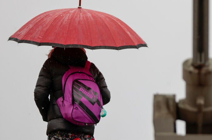 Una mujer se protegen de la lluvia con un paraguas