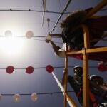 Operarios colocan farolillos en una calle de la Feria de Abril, el año pasado