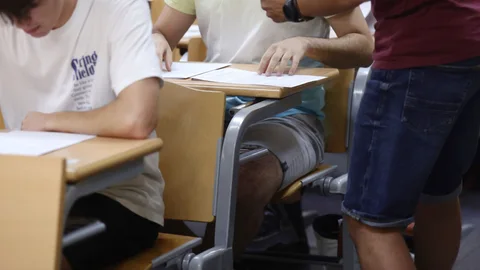 Un profesor reparte exámenes