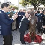 Juanma Moreno aplaude a Antonio González Gallardo, Antoñito, que abraza a la estatua dedicada a él 