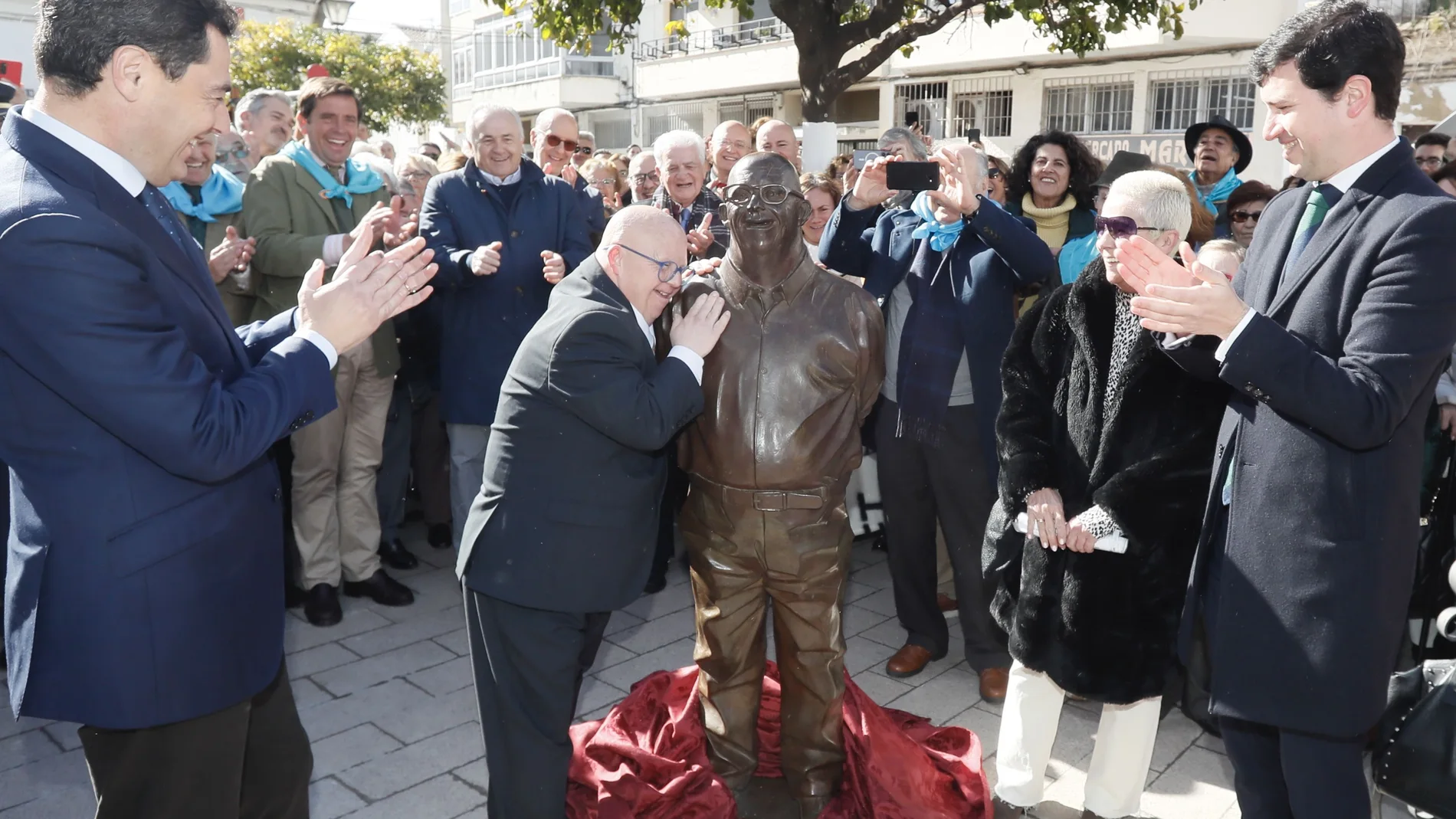 Juanma Moreno aplaude a Antonio González Gallardo, Antoñito, que abraza a la estatua dedicada a él 