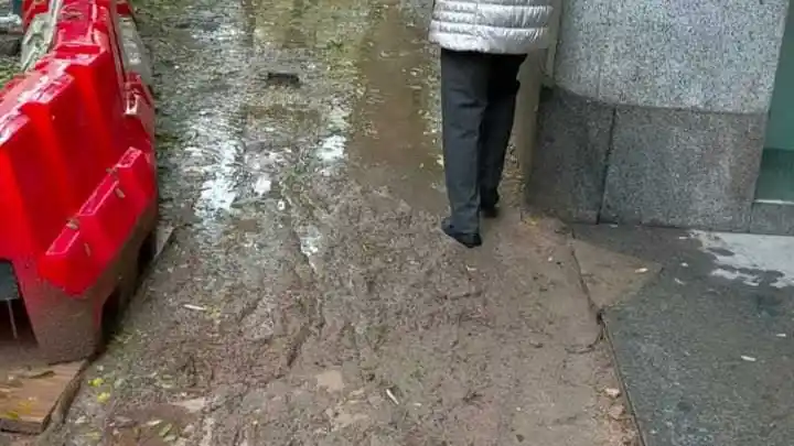 Una señora camina por la calle Ponzano durante las obras en un camino de barro lleno de obstáculos
