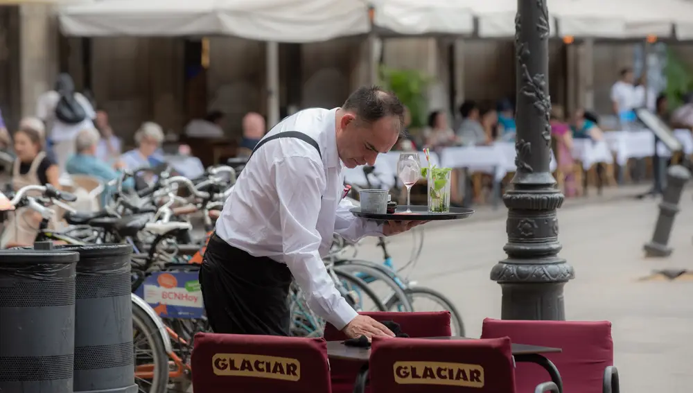 Un camarero limpia una mesa en una terraza