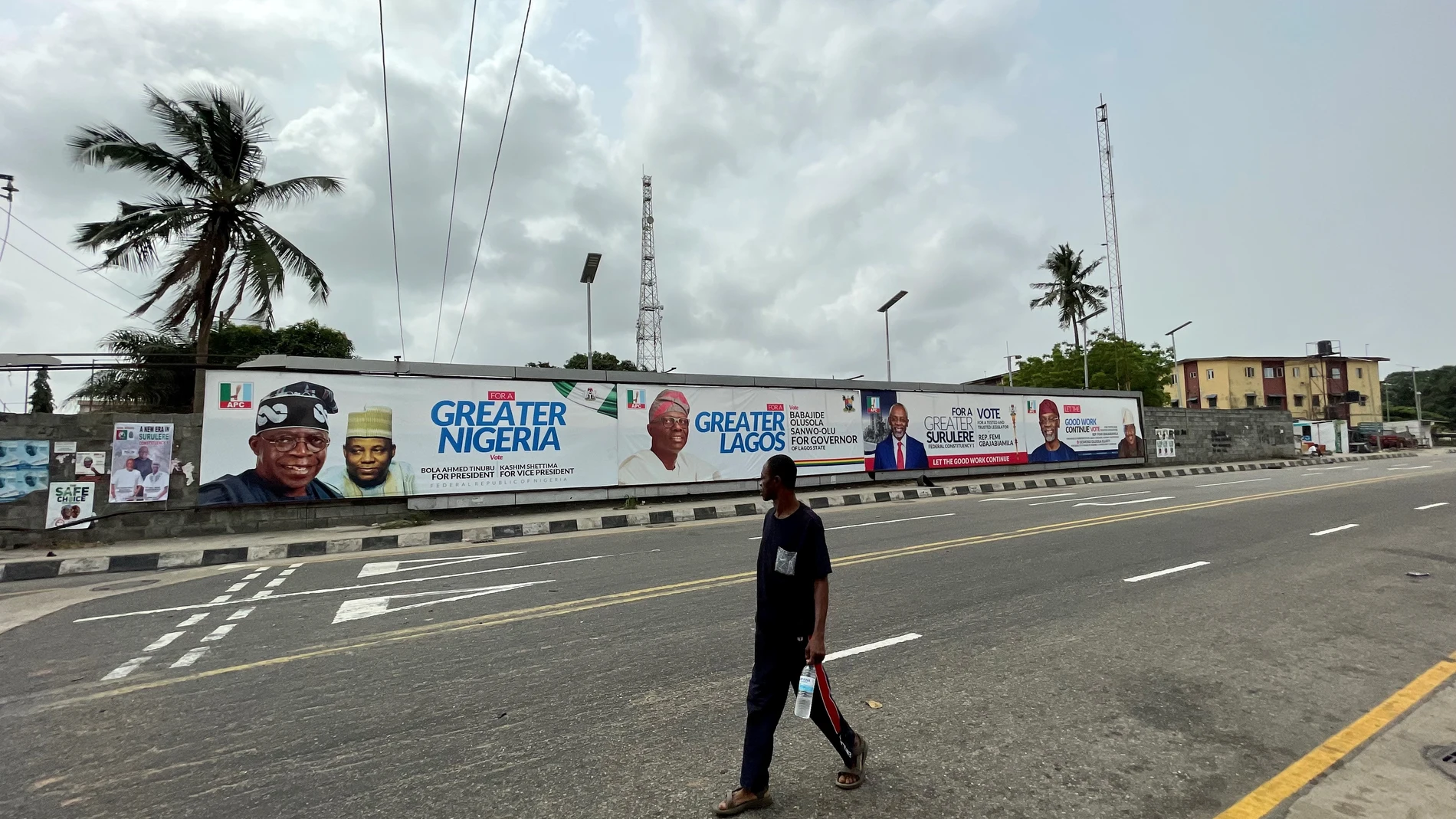 Un ciudadano de Lagos camina junto a los carteles electorales del APC. 