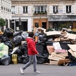 Un parisino pasa junto a contenedores rebosantes de basura tras la manifestación del sábado