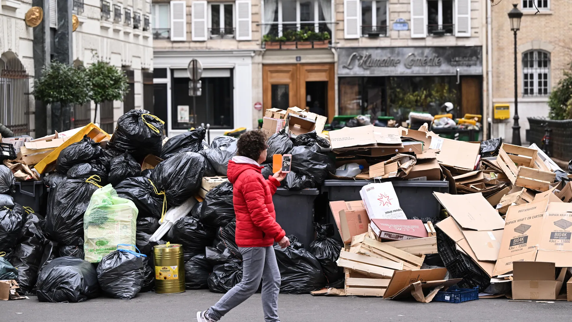 Un parisino pasa junto a contenedores rebosantes de basura tras la manifestación del sábado