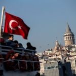  Personas que viajan en ferry desde Asia hasta Europa otean la Torre de Gálata, en Estambul, Turquía