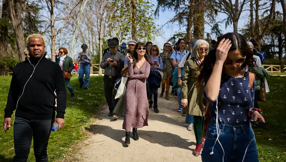 Asistentes al paseo literario 'De Fieras a Feria' recorren El Retiro este lunes mientras escuchan con sus auriculares historias de Patti Smith, Pio Baroja, Gloria Fuertes y otros poetas.