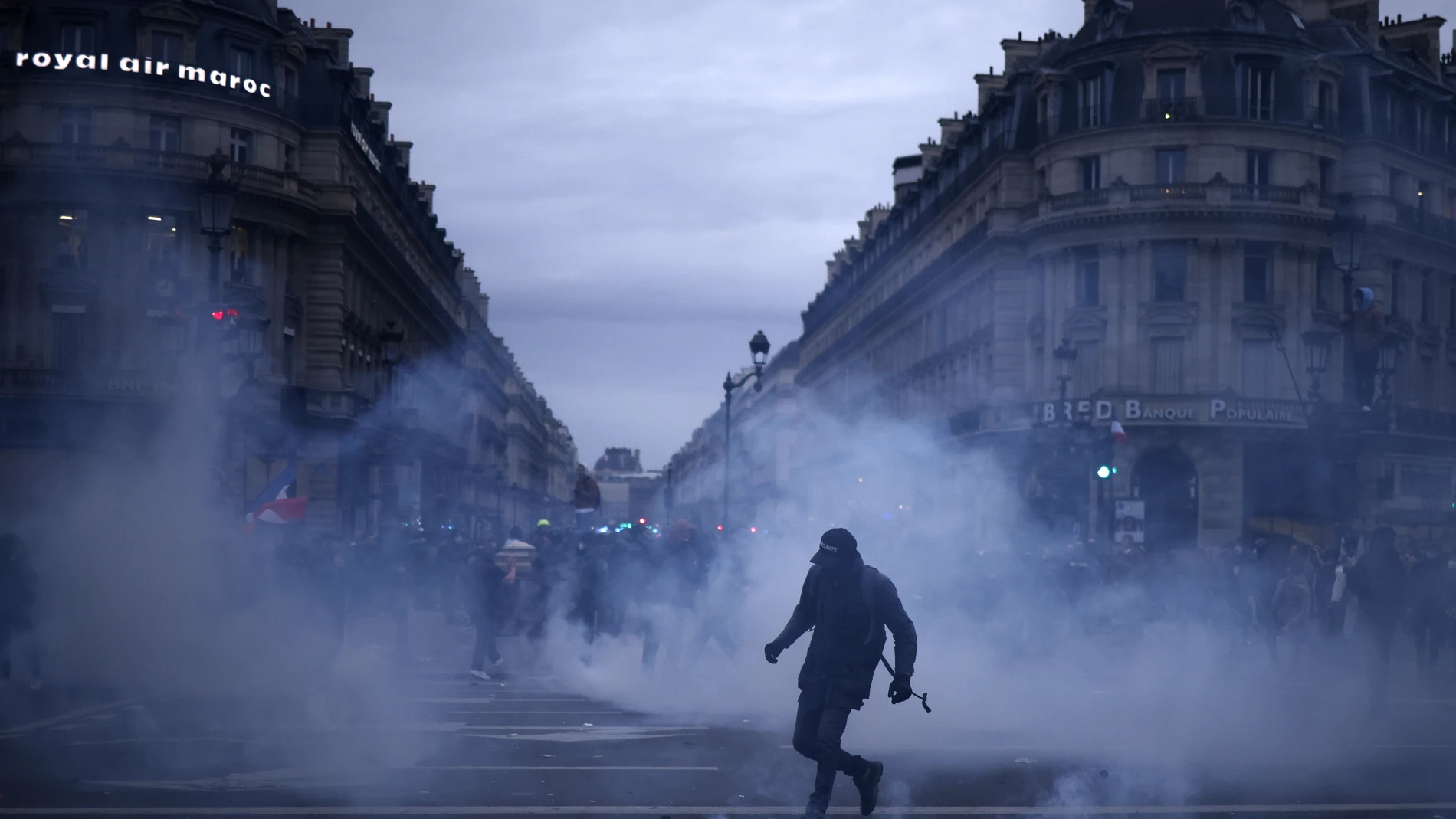 Paris (France), 23/03/2023.- A protester stands in tear gas fumes during clashes with anti-riot police as thousands of people participate in a protest against the government's reform of the pension system in Paris, France, 23 March 2023. Protests continue in France after the prime minister announced on 16 March 2023 the use of Article 49 paragraph 3 (49.3) of the French Constitution to have the text on the controversial pension reform law - raising retirement age from 62 to 64 - be definitively adopted without a vote. (Protestas, Francia, Estados Unidos) EFE/EPA/YOAN VALAT