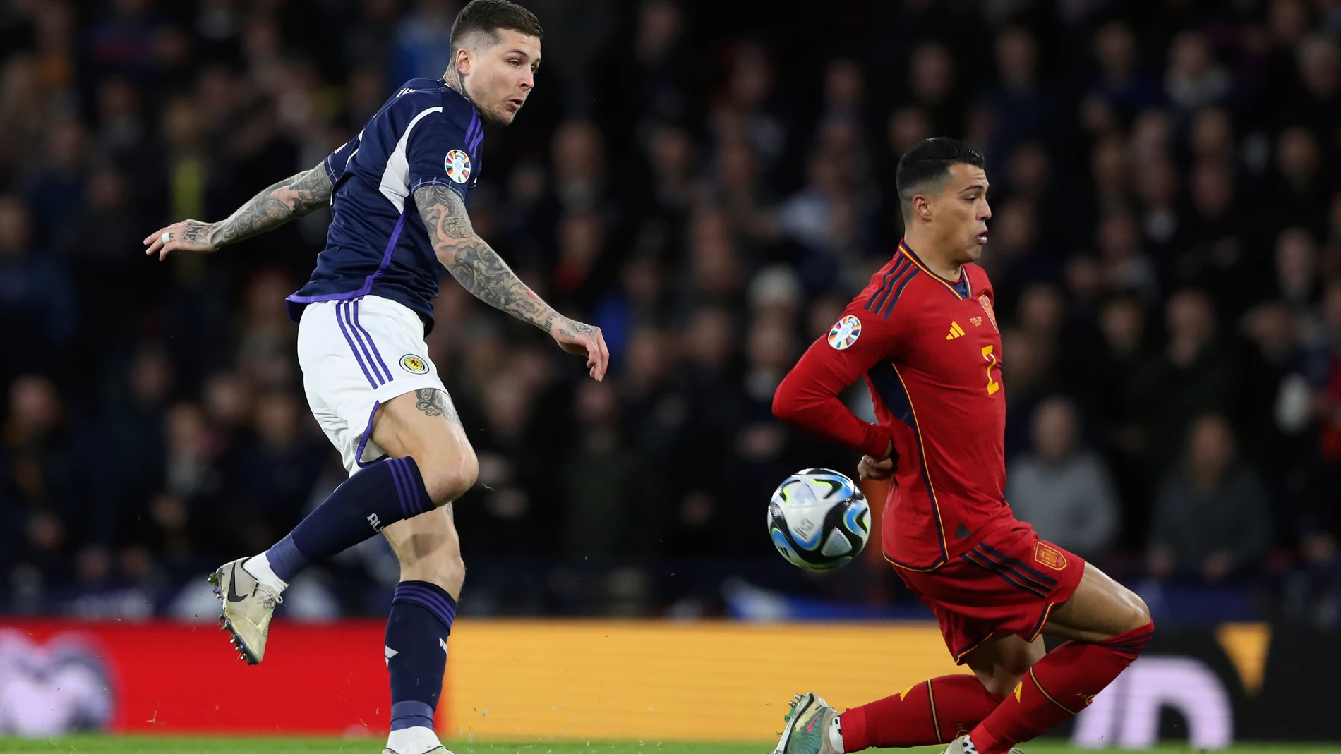 Scotland's Lyndon Dykes, left, attempts a goal as Spain's Pedro Porro tries to stop the ball during the Euro 2024 group A qualifying soccer match between Scotland and Spain at the Hampden Park stadium in Glasgow, Scotland, Tuesday, March 28, 2023. (AP Photo/Scott Heppell)