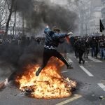 Un manifestante salta sobre un fuego durante la última jornada de protestas y huelgas contra la reforma de las pensiones de Emmanuel Macron, en París