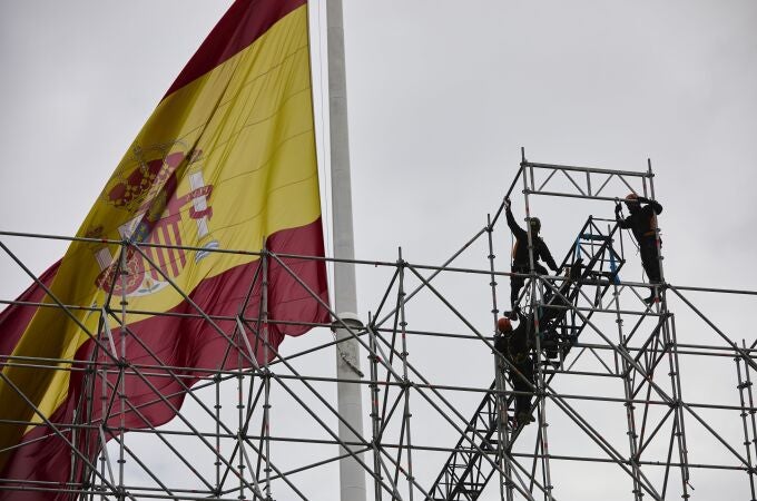 Trabajadores en un andamio en la plaza de Colón, con la bandera de España, en Madrid