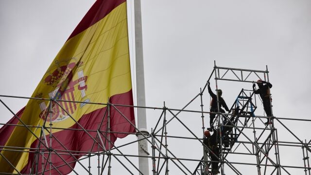 Trabajadores en un andamio en la plaza de Colón, con la bandera de España, en Madrid