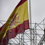 Trabajadores en un andamio en la plaza de Colón, con la bandera de España, en Madrid