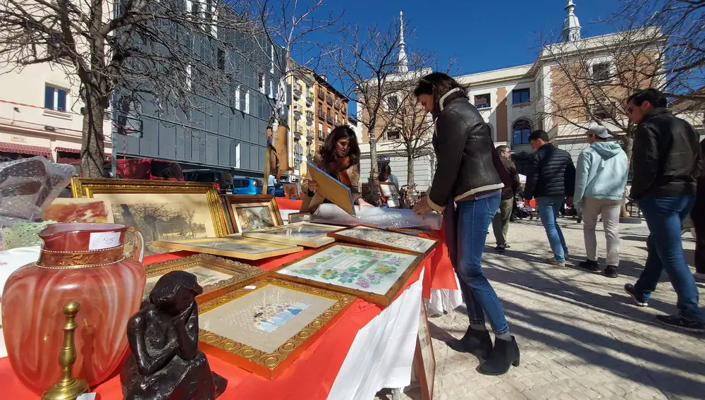 Elena Martínez muestra a una clienta uno de sus cuadros de punto de cruz hechos a mano el pasado 4 de marzo en su puesto de 'Los Sábados del Rastro'.