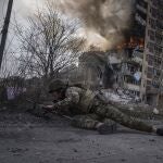 A Ukrainian police officer takes cover in front of a burning building that was hit in a Russian airstrike in Avdiivka, Ukraine.