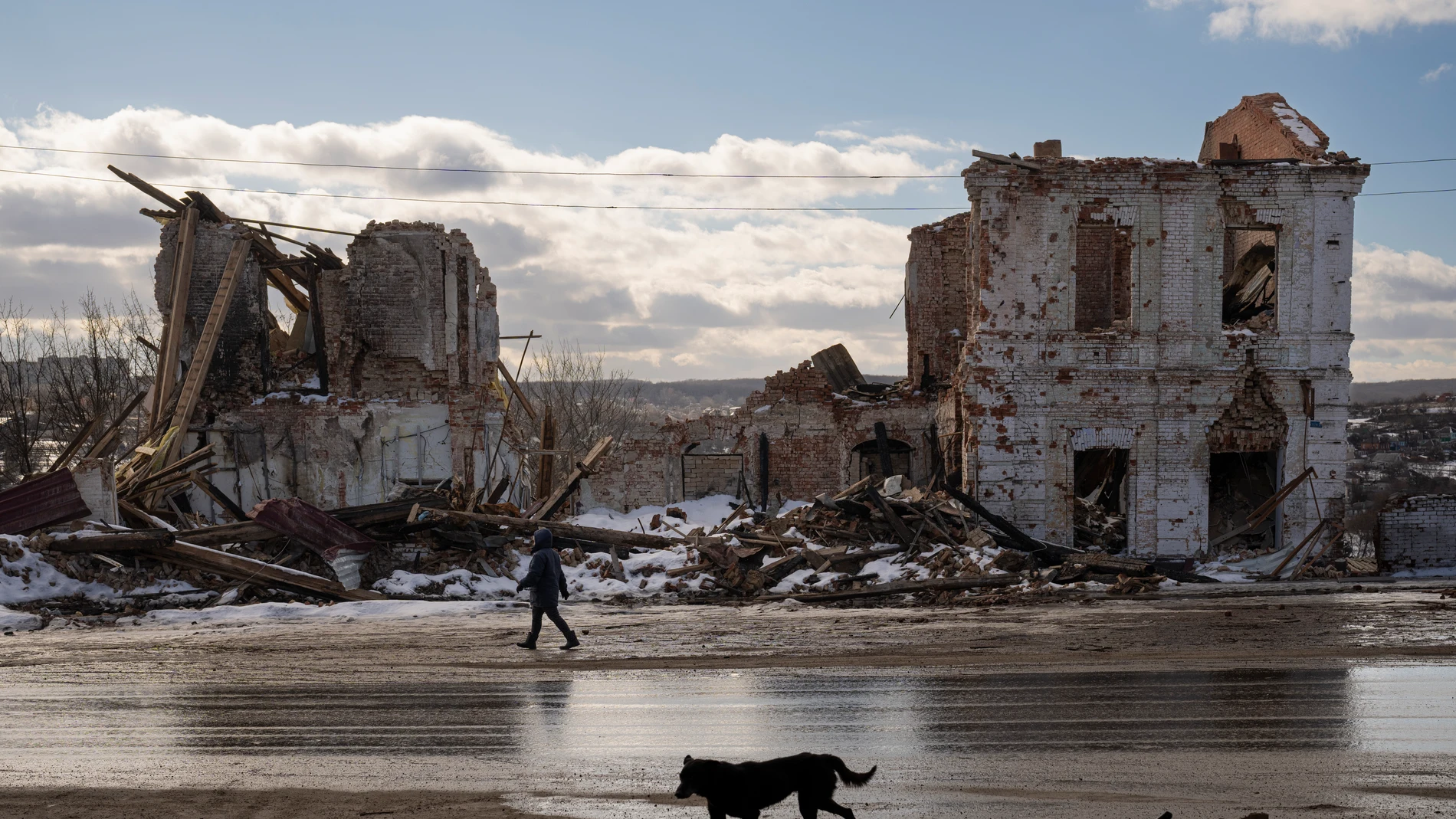 FILE - A woman walks by a building destroyed by a Russian strike in Kupiansk, Ukraine, Monday, Feb. 20, 2023. An international arrest warrant for President Vladimir Putin raises the prospect of justice for the man whose country invaded Ukraine but complicates efforts to end that war in peace talks. (AP Photo/Vadim Ghirda, File)