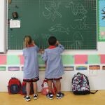 Dos niños pintan en una pizarra el día de inicio del curso en el colegio 