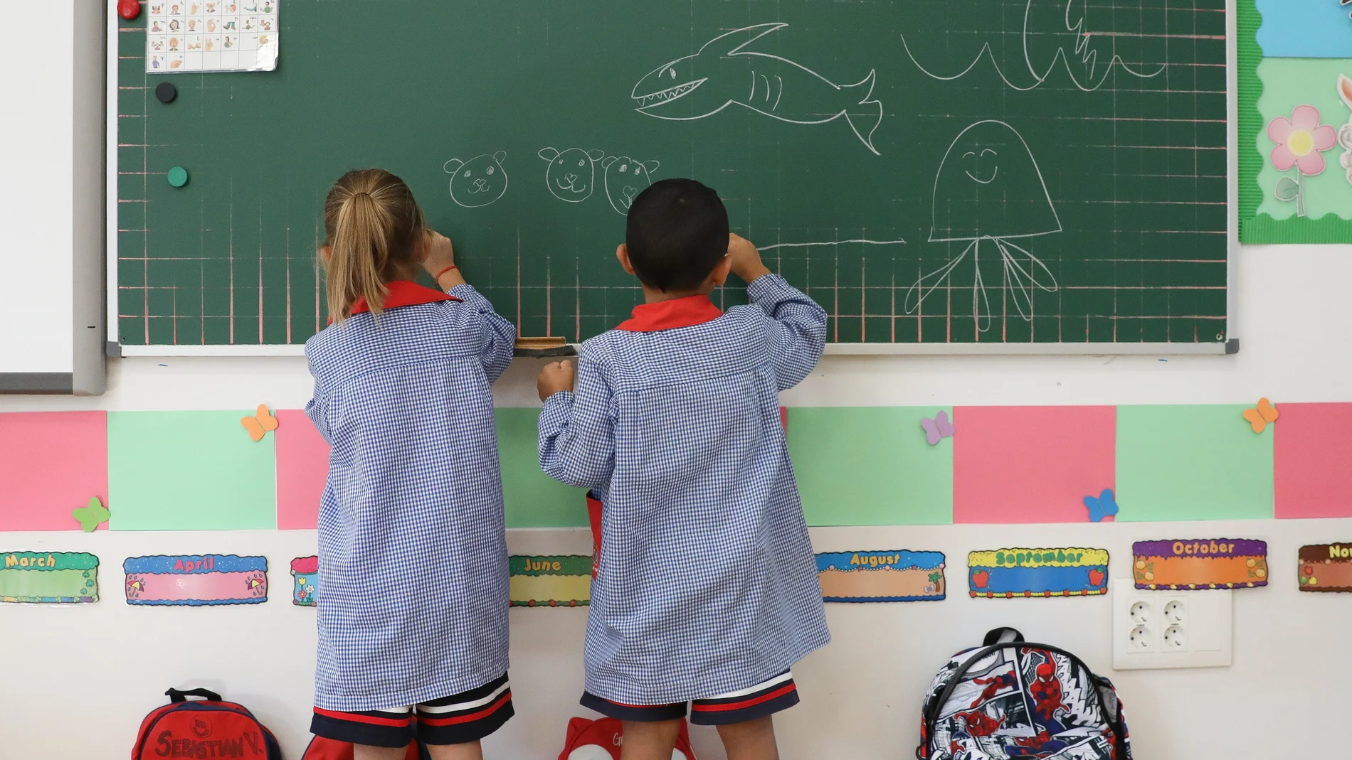 Dos niños pintan en una pizarra el día de inicio del curso en el colegio 