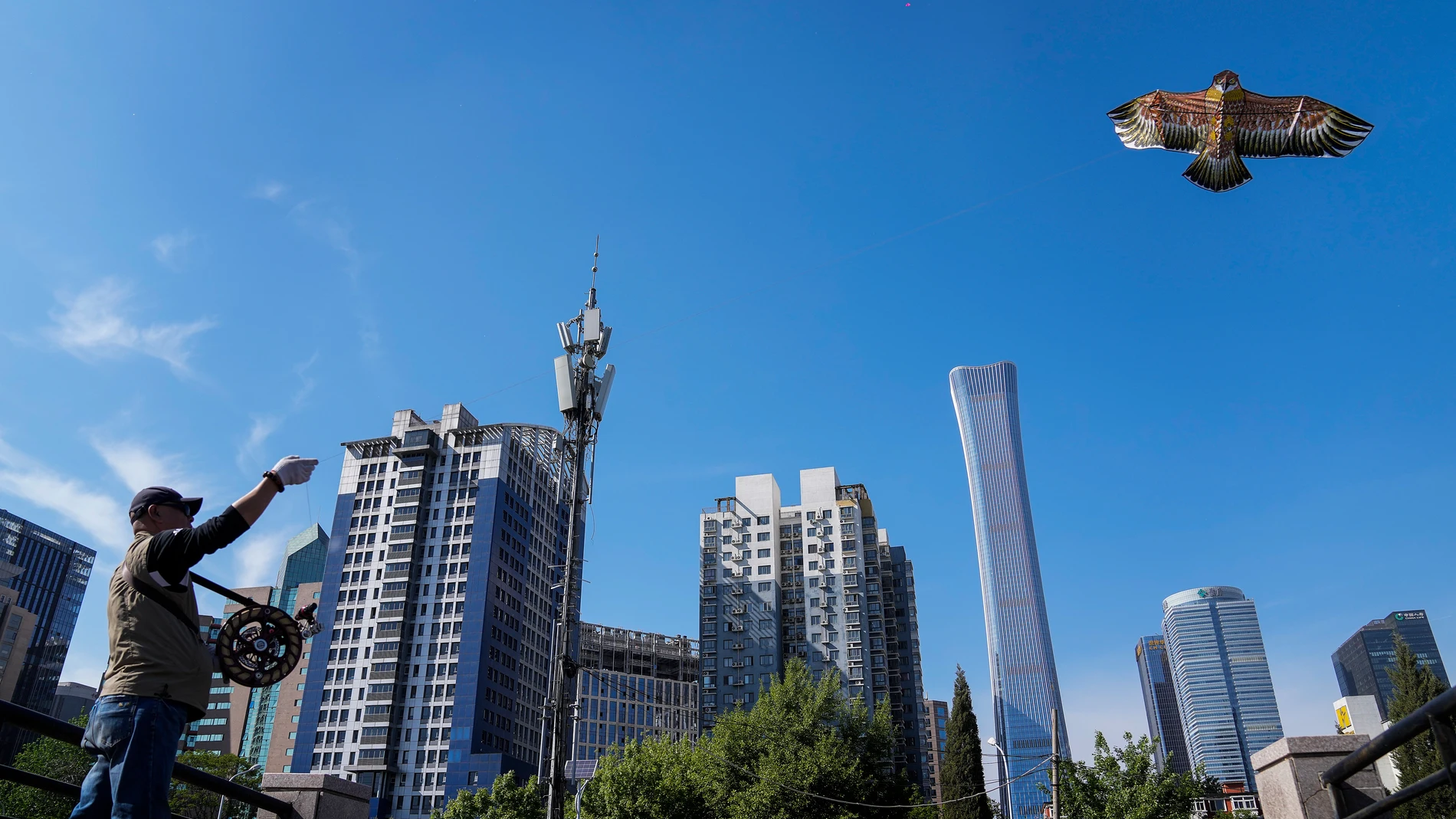 A man flies a kite at a public park against the capital city tallest skyscraper China Zun Tower and office buildings in the central business district in Beijing, Tuesday, April 18, 2023. China's economic growth accelerated in the latest quarter as consumer flocked back to shops and restaurants following the abrupt end of anti-virus controls. (AP Photo/Andy Wong)