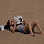 Una mujer toma el sol en la playa de la Barceloneta