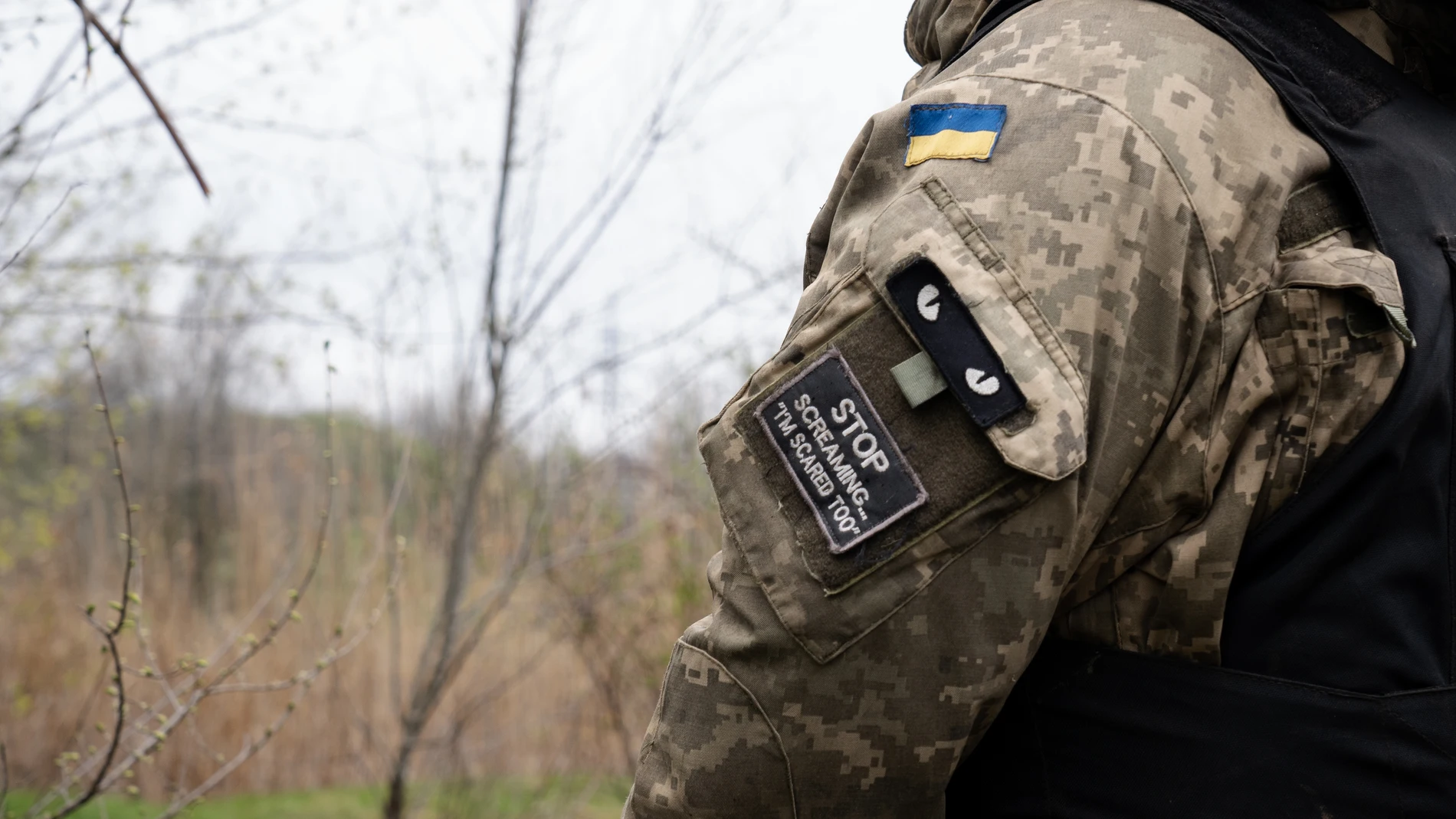April 15, 2023, Bakhmut, Ukraine: A patch written 'stop screaming â€?I'm scared too'' is seen on a Ukrainian soldier's army uniform, alongside a Ukrainian flag in the Ukrainian position near Bakhmut. Ukrainian armed force is fighting intensely in Bakhmut and the surrounding area as Russian forces are getting ever closer to taking the eastern city of Ukraine. The battle of Bakhmut is now known as 'the bloodiest' and 'one of the longest fight', it has become one of the most significant fights in the war between Ukraine and Russia. 15/04/2023