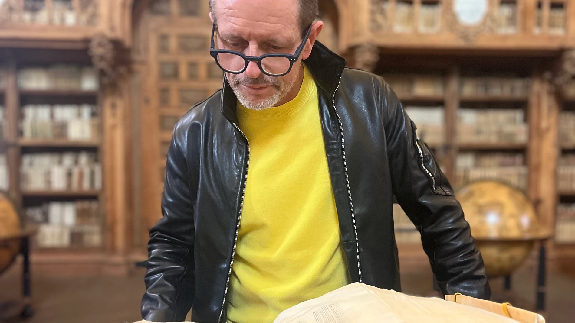 El novelista observa un libro en la histórica biblioteca de la Universidad de Salamanca