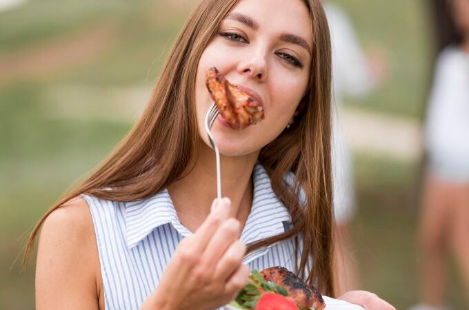 Mujer comiendo un filete de carne
