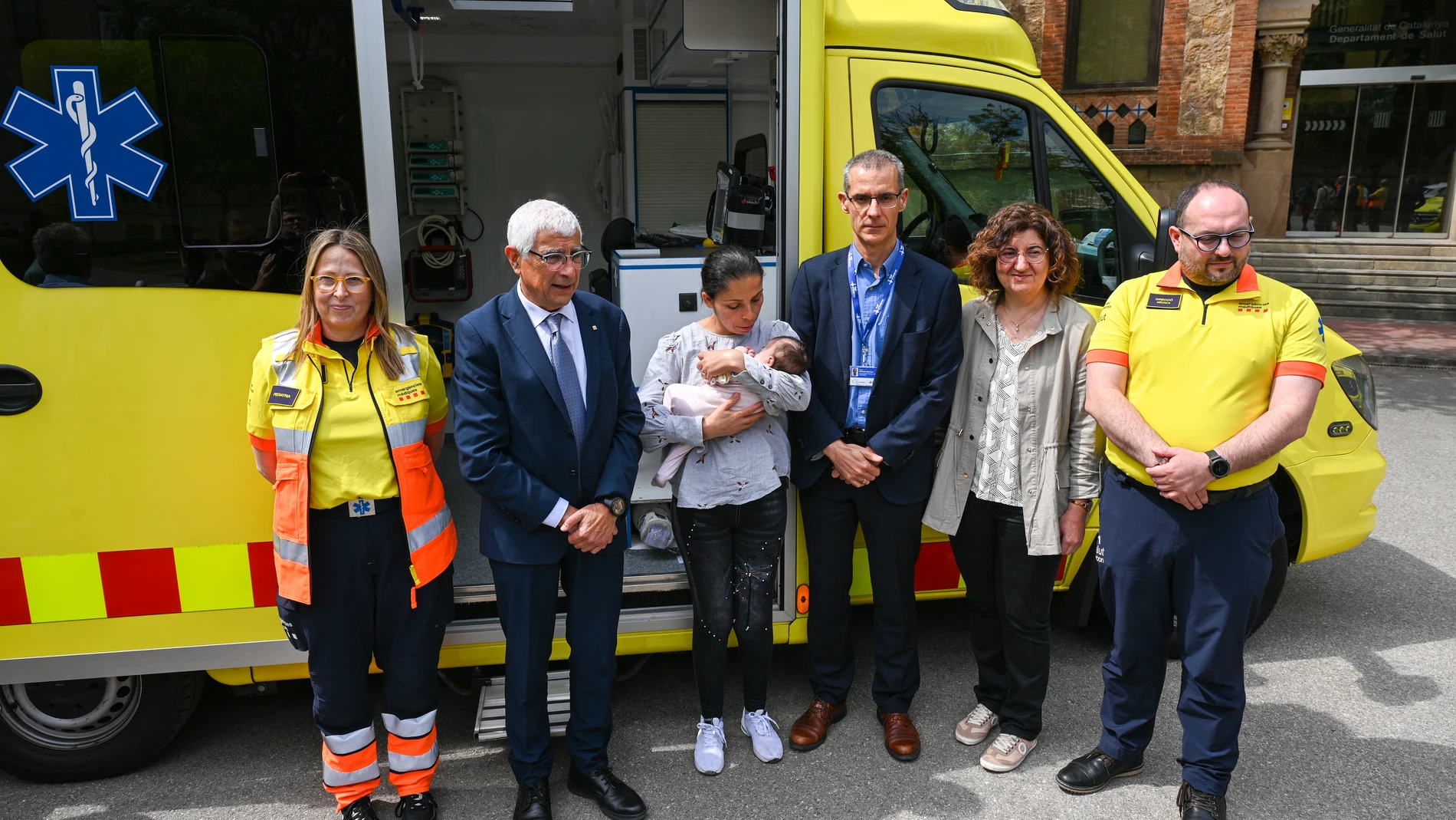 Representantes de todos los dispositivos del programa de traslado con ECMO pediátrico, con el conseller Balcells, Aisha y su madre, frente a la ambulancia especializada