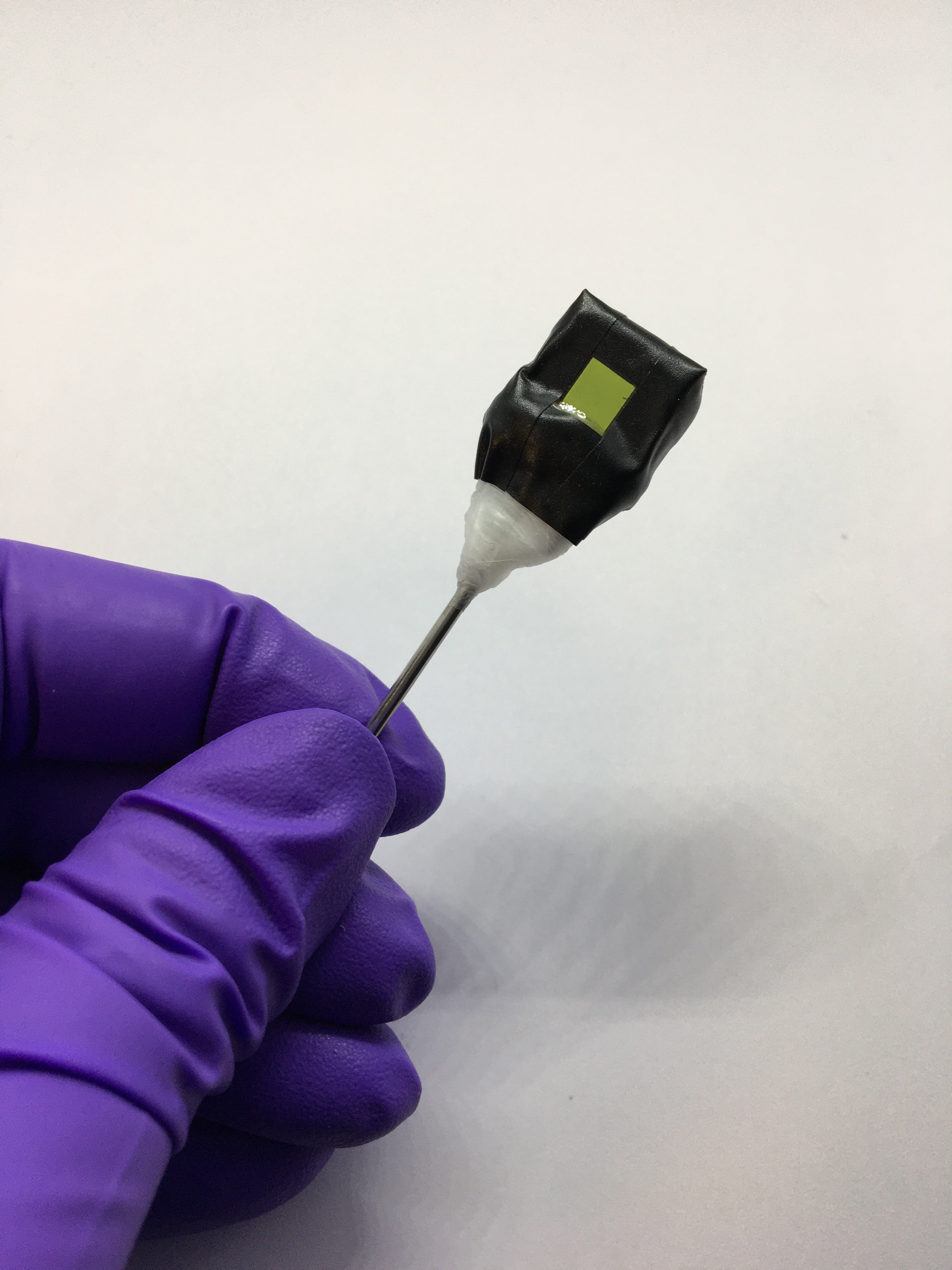 Una hoja artificial independiente sujeta a una varilla metálica. En la fotografía se ve el lado del fotoánodo (cuadrado verde). 