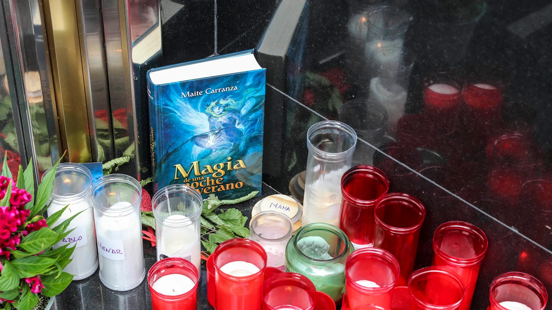 Velas, flores y un libro en el portal de la calle Facetos de Oviedo en el que vivían las mellizas Alexandra y Anastasia