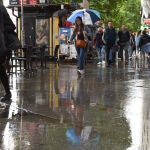 Varias personas pasean bajo la lluvia, a 23 de mayo de 2023, en Madrid (España)