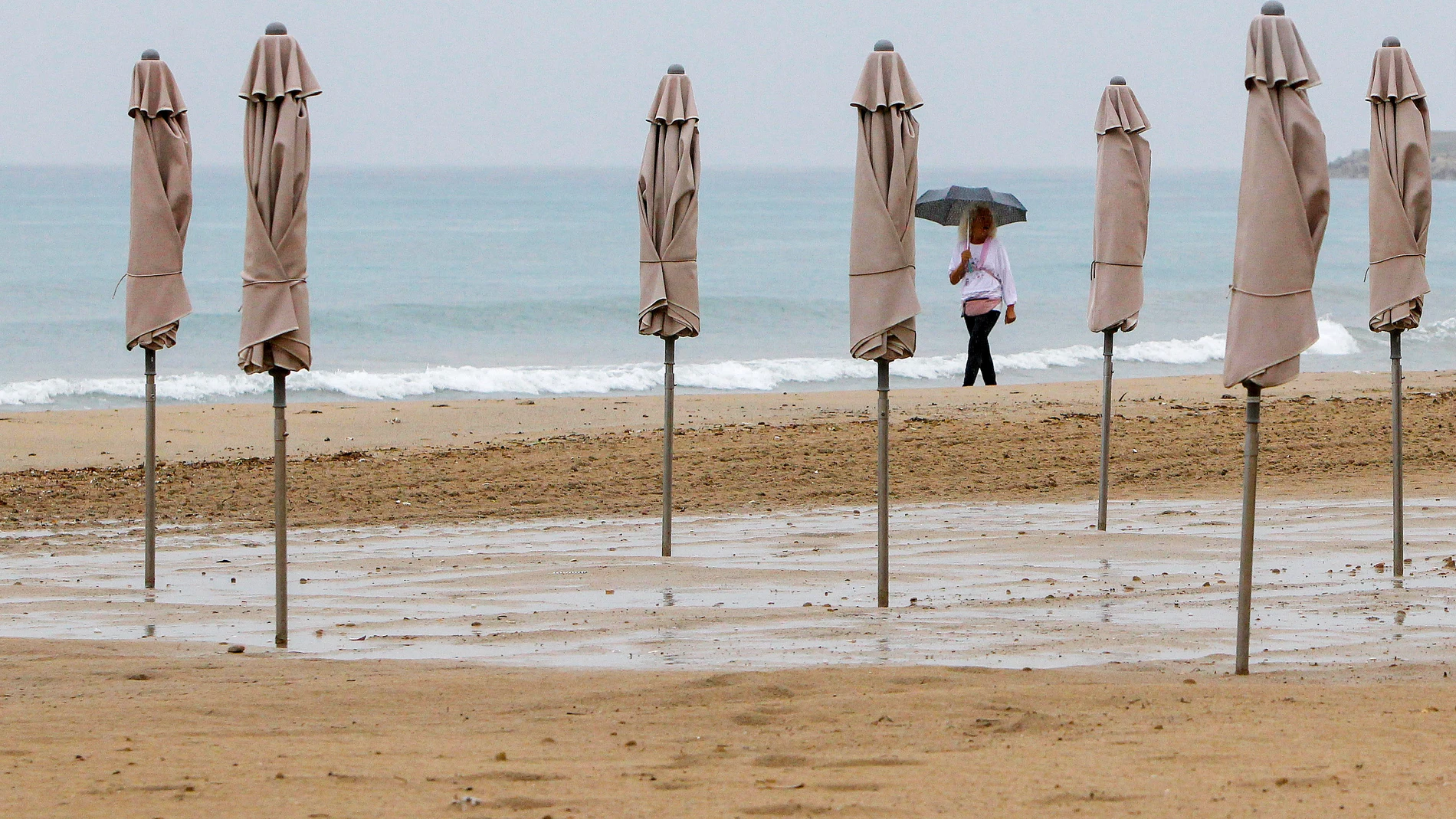 GRAFCVA3562. ALICANTE, 24/05/2023.- Una persona pasea bajo la lluvia por la playa de El Postiguet de Alicante cuando el Centro de Coordinación de Emergencias ha dado por concluida la situación de preemergencia por lluvias y tormentas nivel naranja en la provincia de Alicante y el interior sur y el litoral de la de Valencia. EFE/Morell 
