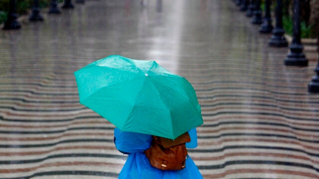  Una persona pasea bajo la lluvia por la explanada de Alicante