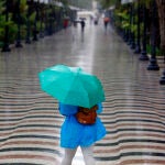  Una persona pasea bajo la lluvia por la explanada de Alicante