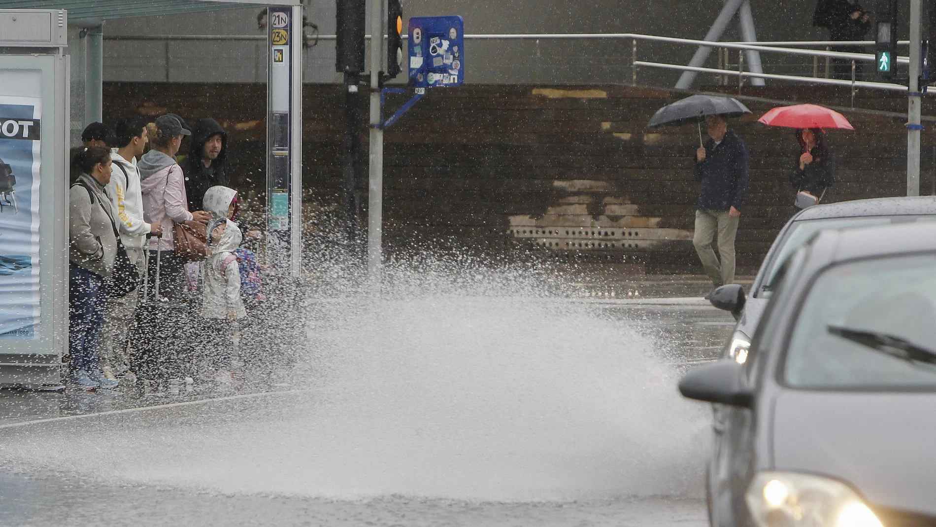 ALICANTE, 24/05/2023.- Varias personas se resguardan de la lluvia en una parada de autobús cuando el Centro de Coordinación de Emergencias ha dado por concluida la situación de preemergencia por lluvias y tormentas nivel naranja en la provincia de Alicante y el interior sur y el litoral de la de Valencia.