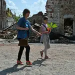 Mujeres pasan junto a un paque de Járkiv golpeado por los bombardeos rusos