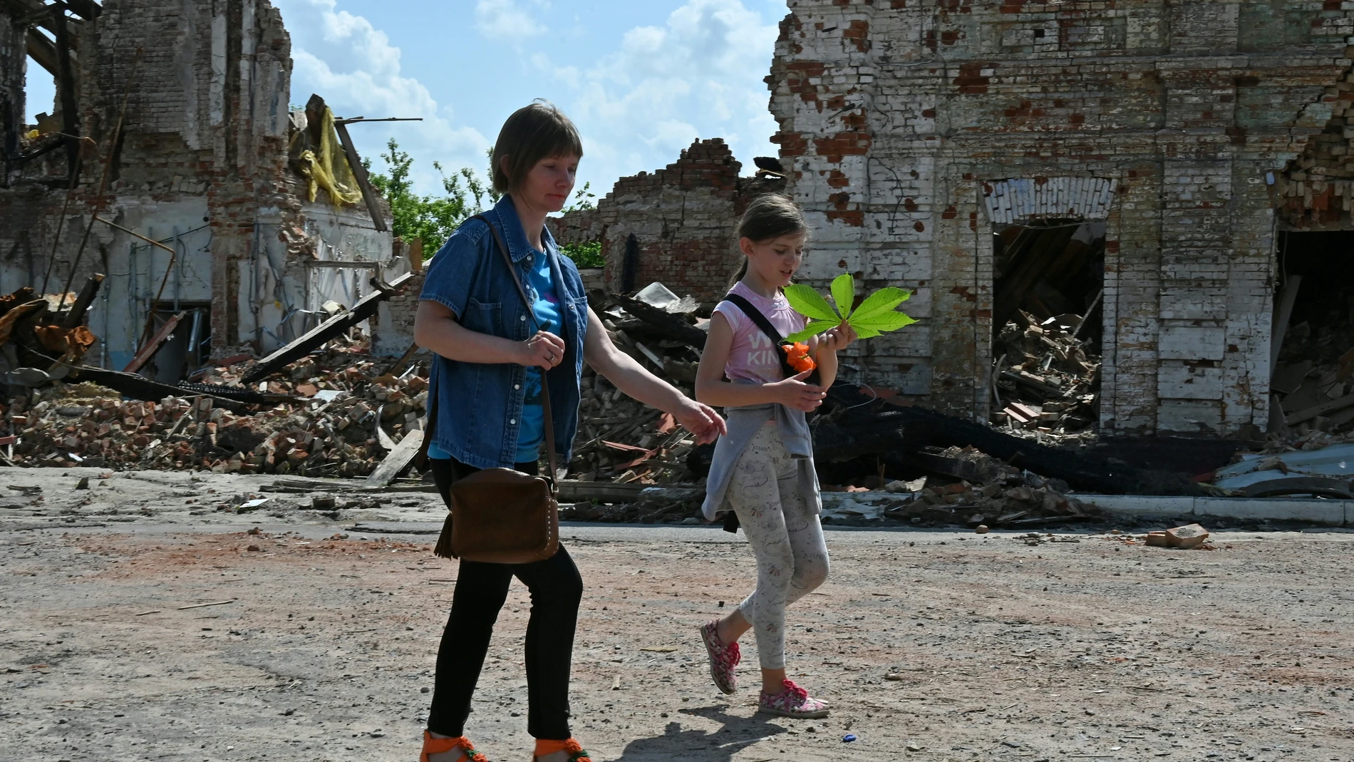 Mujeres pasan junto a un paque de Járkiv golpeado por los bombardeos rusos