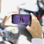 Un hombre observa en su móvil la imagen de la secretaria general de Podemos, Ione Belarra durante la rueda de prensa celebrada este viernes en la sede del partido en Madrid donde ha anunciado que Podemos concurrirá a las elecciones generales del 23 de julio con la coalición de Sumar. 