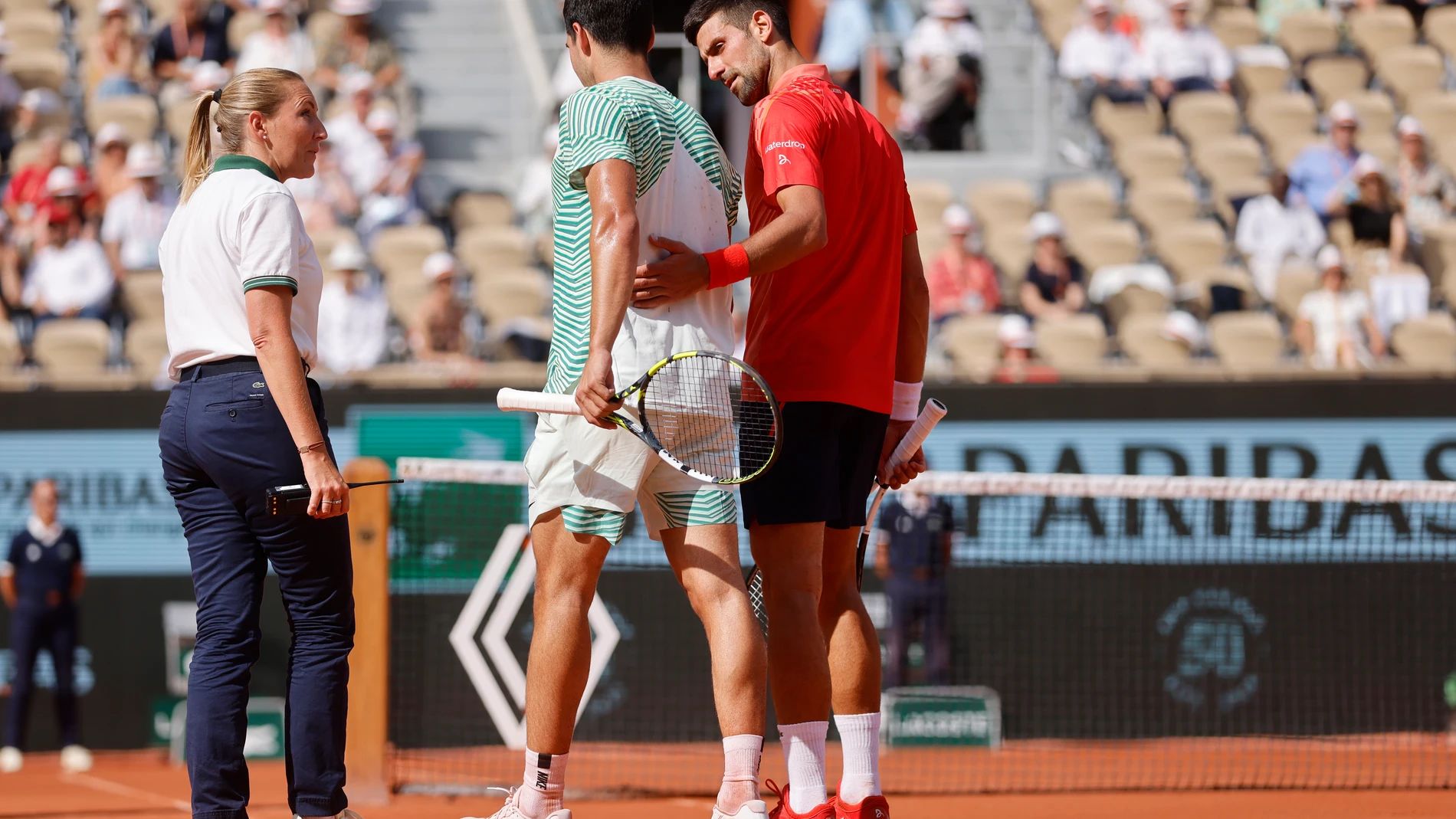 Spain's Carlos Alcaraz, center, walks with the help of Serbia's Novak Djokovic, right, as he is injured during their semifinal match of the French Open tennis tournament at the Roland Garros stadium in Paris, Friday, June 9, 2023. (AP Photo/Jean-Francois Badias)