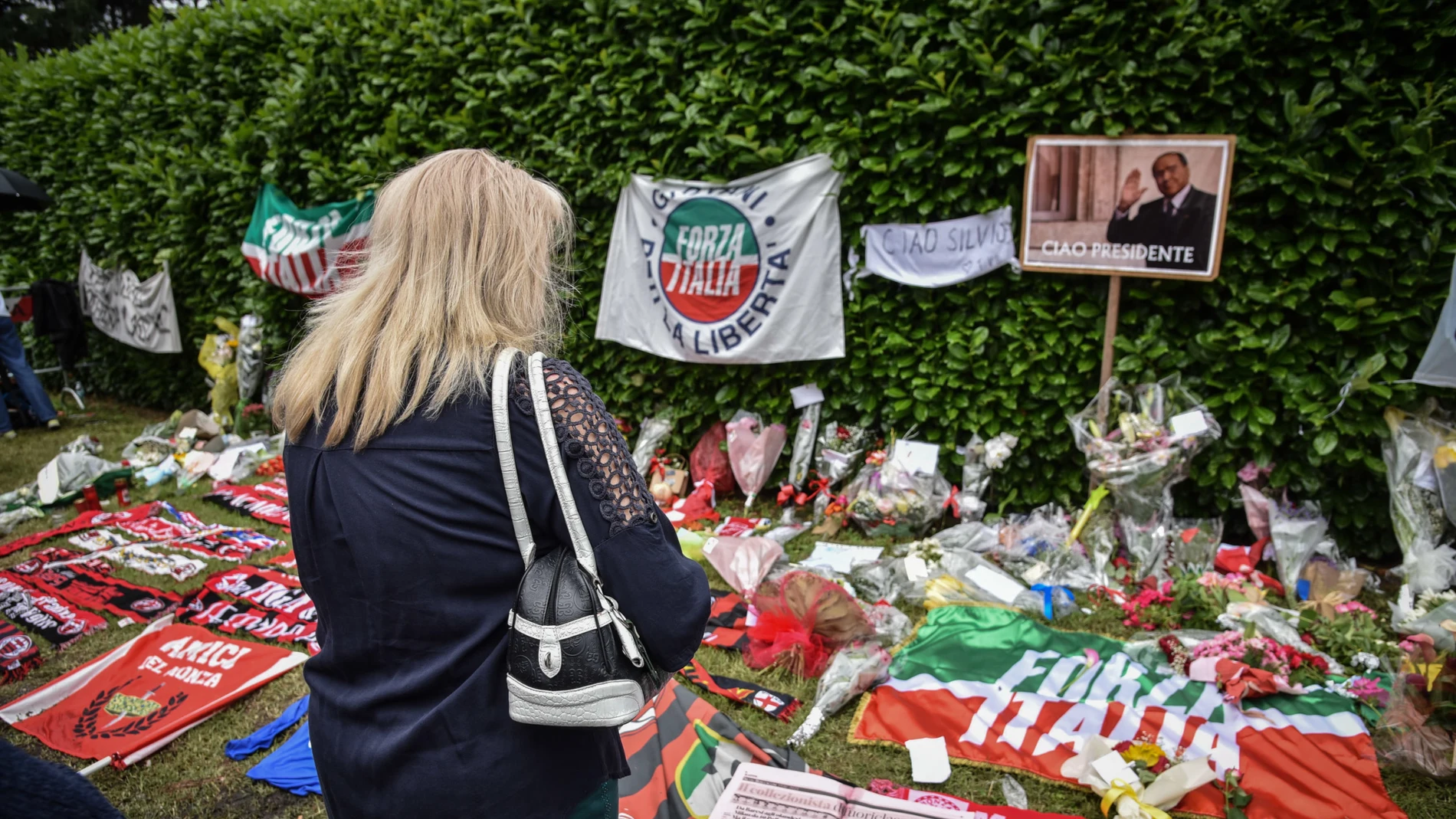 Milan (Italy), 13/06/2023.- A woman looks at flowers, banners and scarves near the entrance to Villa San Martino in Arcore, where the coffin of Silvio Berlusconi was brought a day earlier, near Milan, northern Italy, 13 June 2023. Silvio Berlusconi died at the age of 86 on 12 June 2023 at San Raffaele hospital in Milan, where he was hospitalized again since last 09 June. The Italian media tycoon and Forza Italia (FI) party founder, dubbed as 'Il Cavaliere' (The Knight), served as prime minist...