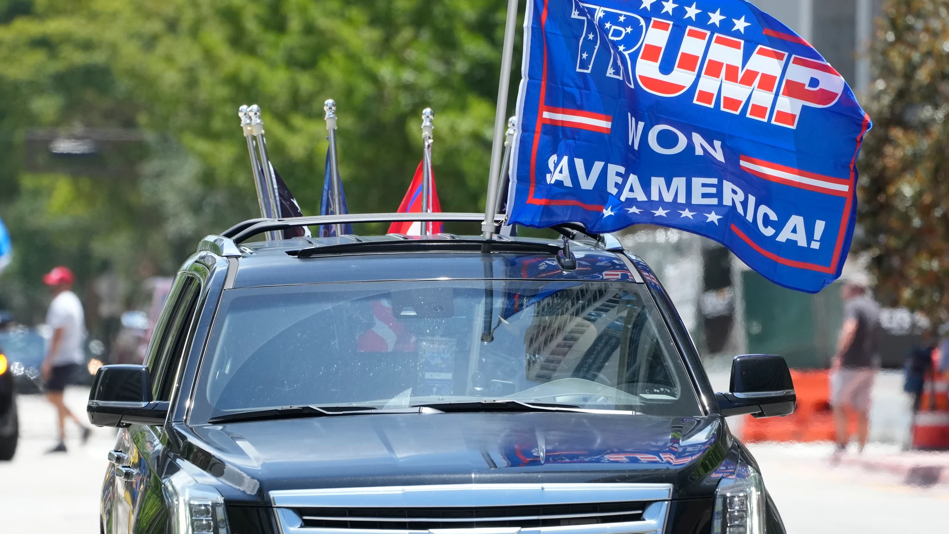 Un simpatizante de Donald Trump enarbola banderas a favor del expresidente en su automóvil