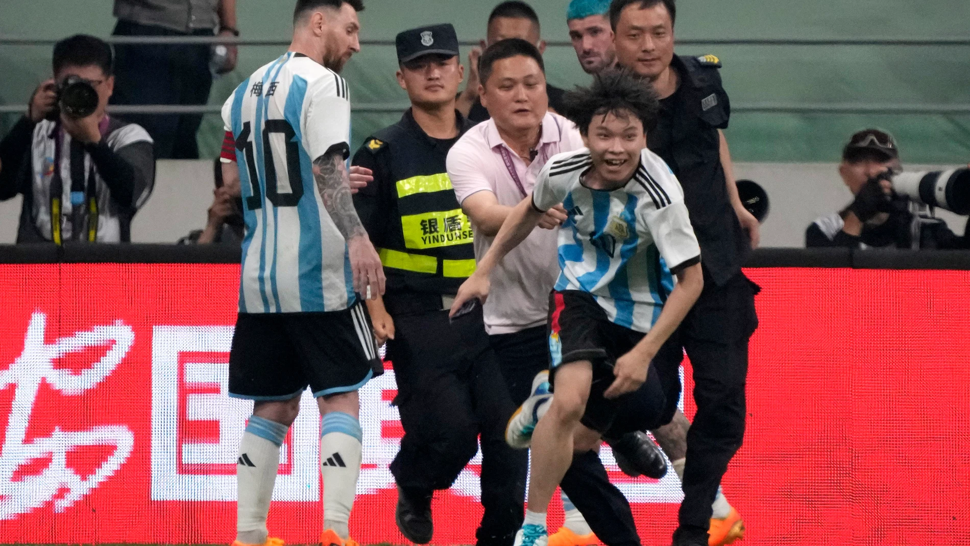 Argentina's Lionel Messi, left, watches as security officers pursue a fan during play on the field in their friendly soccer match against Australia at Workers' Stadium in Beijing, Thursday, June 15, 2023. (AP Photo/Mark Schiefelbein)