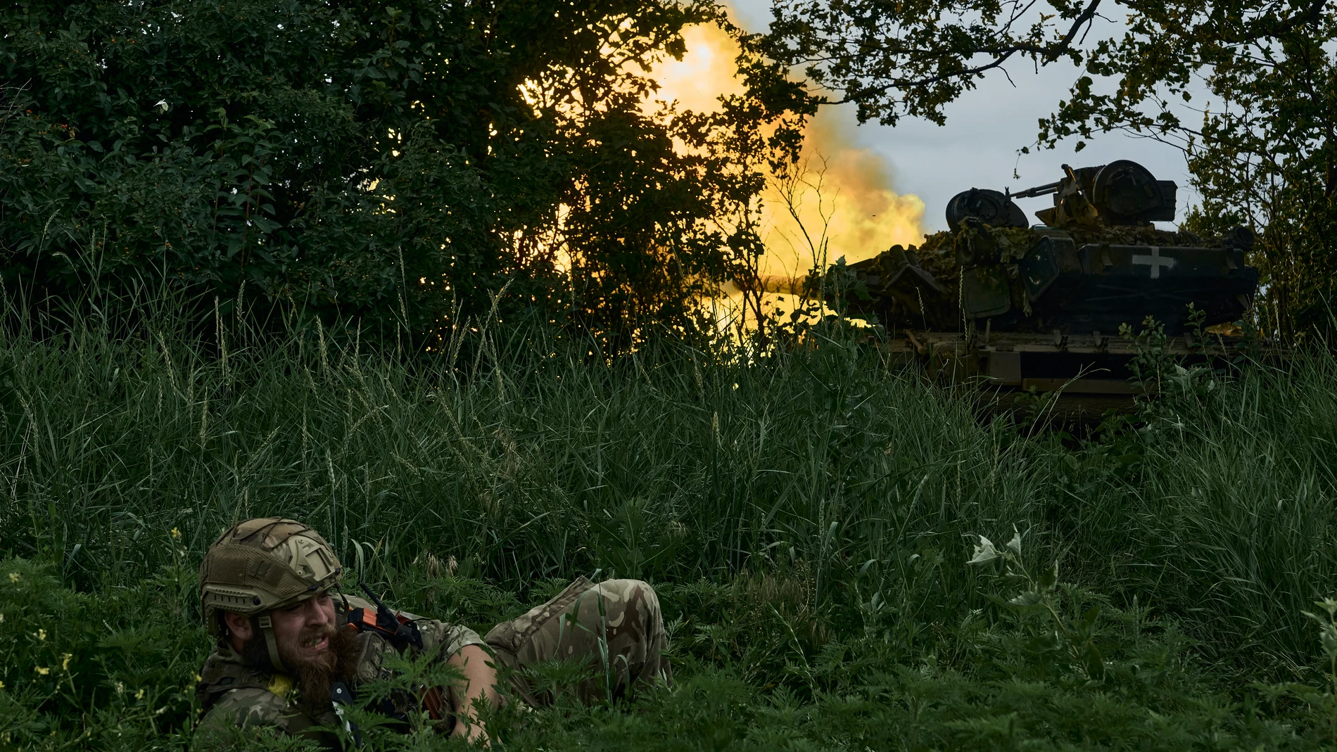 A Ukrainian soldier lies on the ground as a tank fires toward Russian positions at the frontline near Bakhmut, Donetsk region, Ukraine, Saturday, June 17, 2023. (AP Photo/Libkos)