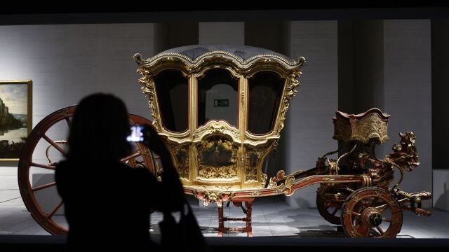 Una visitante observa uno de los carruajes exhibidos en la primera exposición temporal "En Movimiento. Vehículos y carruajes de Patrimono Nacional" que reúne un conjunto de obras que normalmente no se ven expuestas y que son, en muchos casos, únicas en el mundo, este miércoles en la Galería de Colecciones Reales en Madrid. 
